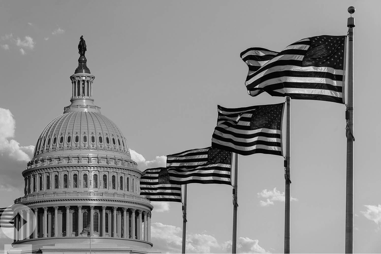 American flag flying over government building in city, blue sky and clouds Capitol building in Washington, DC with United States flags